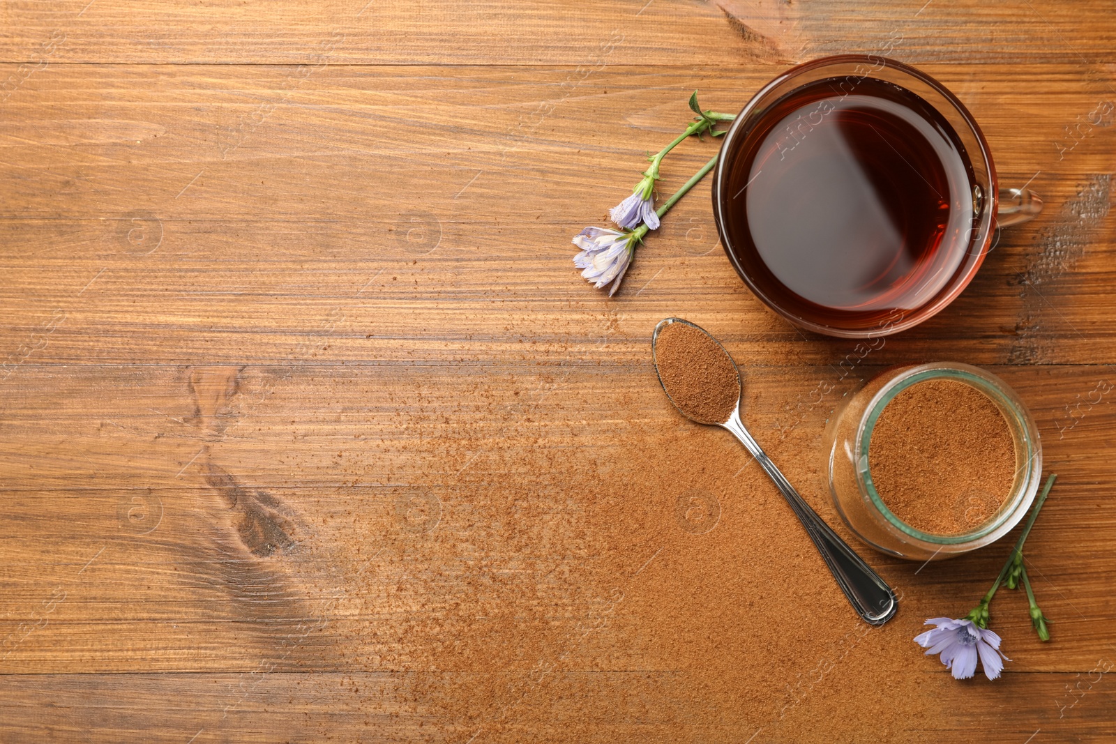 Photo of Cup of delicious chicory drink, powder and flowers on wooden table, flat lay. Space for text