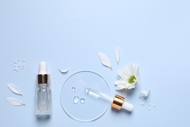 Bottle of cosmetic serum, pipette and flowers on light blue background, flat lay. Space for text