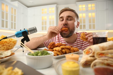 Food blogger eating near microphone at table in kitchen. Mukbang vlog