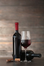 Composition with glass and bottles of red wine on table. Space for text