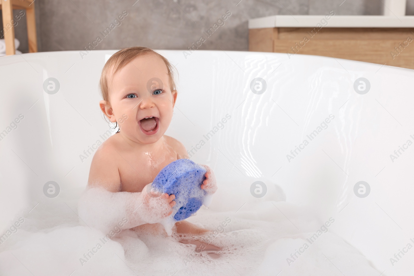 Photo of Cute little baby with sponge bathing in tub at home. Space for text