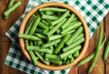 Photo of Fresh green beans in bowl on wooden table, flat lay