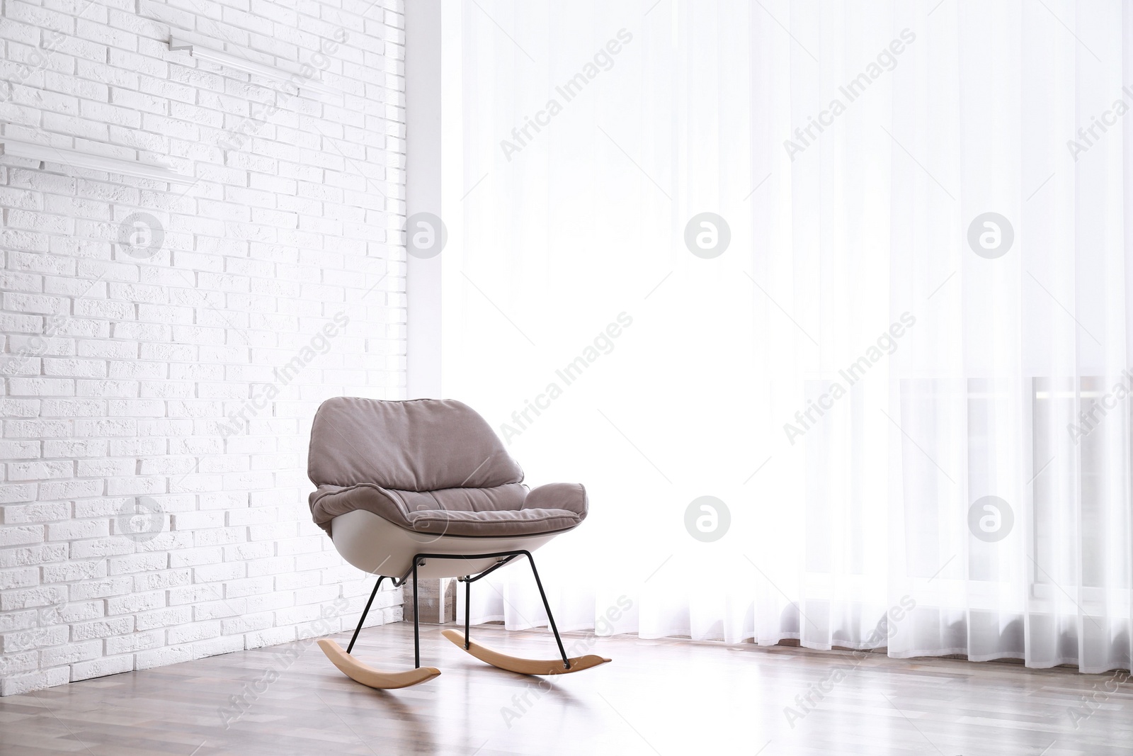 Photo of Comfortable rocking chair near white brick wall. Space for text