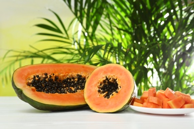 Fresh juicy cut papayas on white table against blurred background, space for text