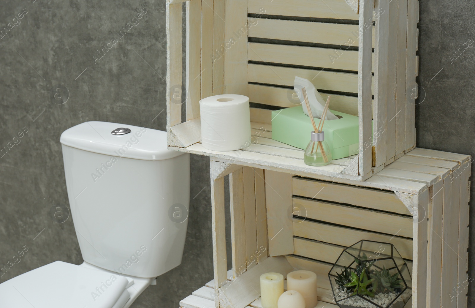 Photo of Toilet bowl and decor elements near grey wall. Bathroom interior