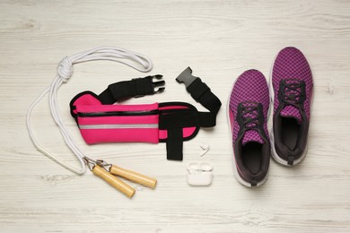 Photo of Flat lay composition with pink waist bag on white wooden table