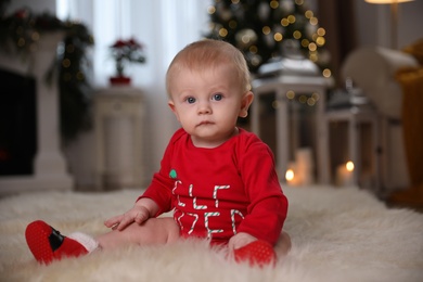 Photo of Cute little baby wearing red bodysuit on floor at home. Christmas celebration