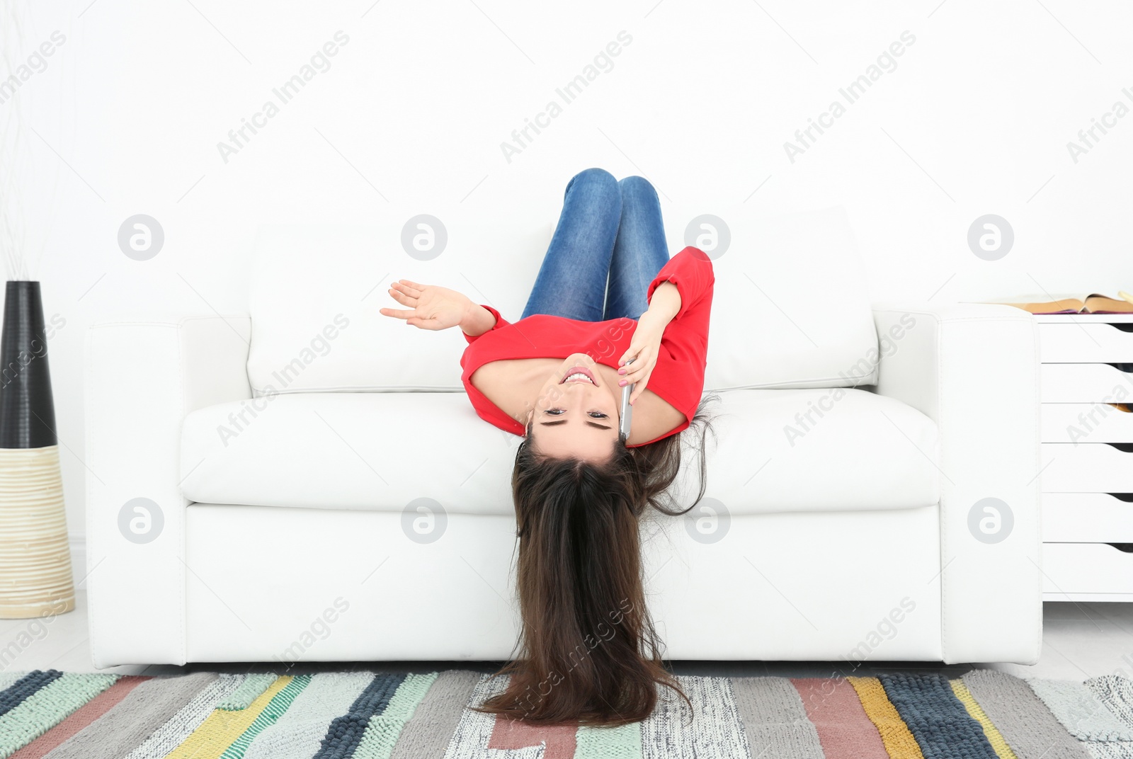 Photo of Young woman talking on mobile phone at home