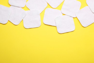 Soft clean cotton pads on yellow background, flat lay. Space for text