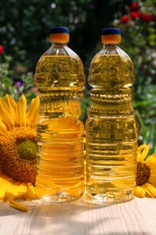 Photo of Bottles of sunflower oil on wooden table outdoors