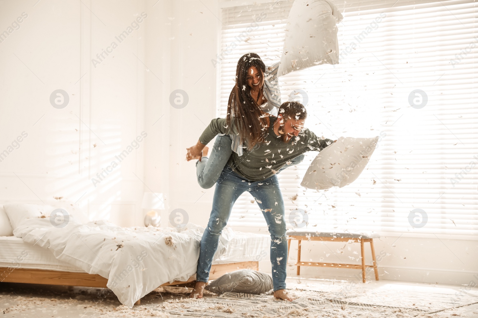 Photo of Happy young couple having fun pillow fight in bedroom