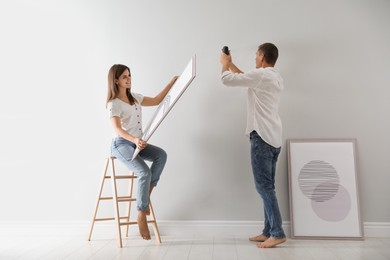 Photo of Couple decorating room with pictures together. Interior design