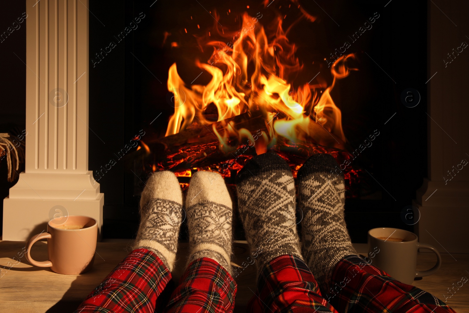 Photo of Couple in knitted socks near fireplace at home, closeup