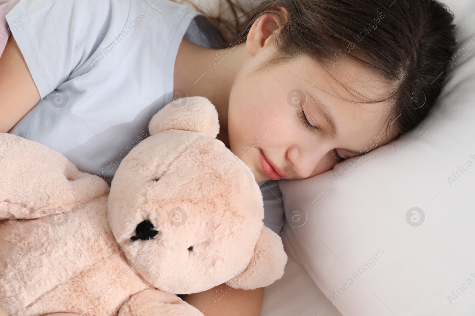 Photo of Beautiful little girl with teddy bear sleeping in bed