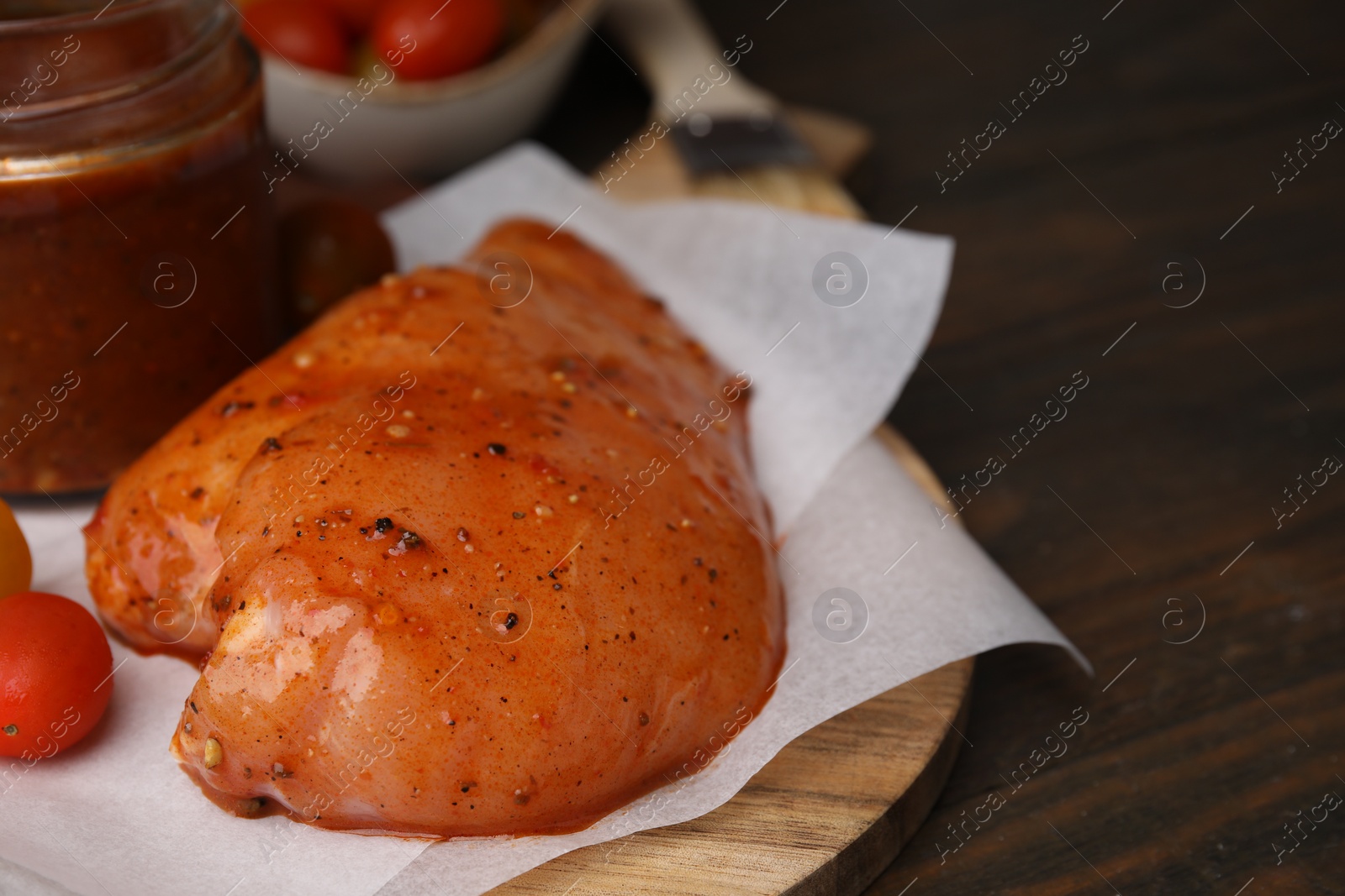 Photo of Raw marinated chicken fillets on wooden table, closeup. Space for text