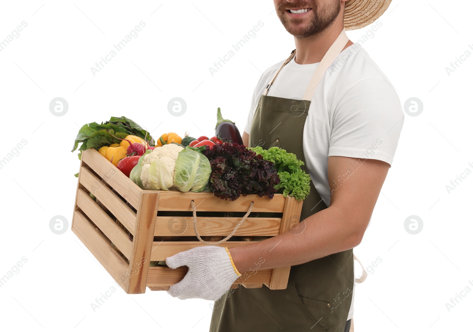 Photo of Harvesting season. Happy farmer holding wooden crate with vegetables on white background, closeup