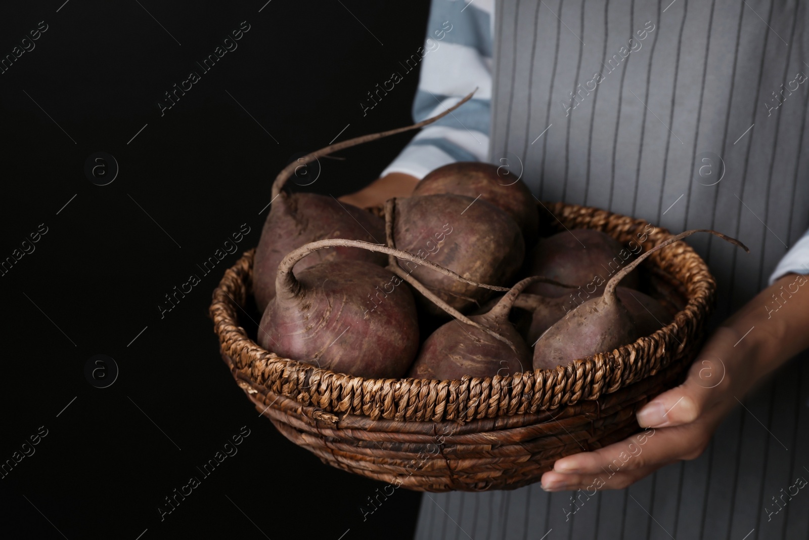 Photo of Woman holding bowl with beets on black background