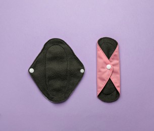 Photo of Reusable cloth menstrual pads on violet background, flat lay