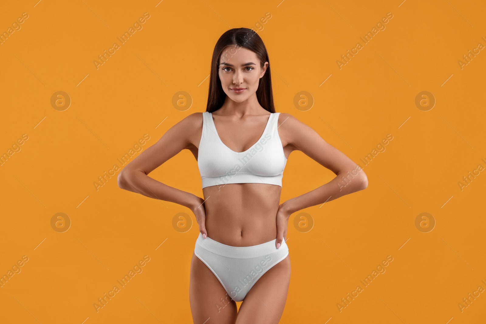 Photo of Young woman in stylish white bikini on orange background