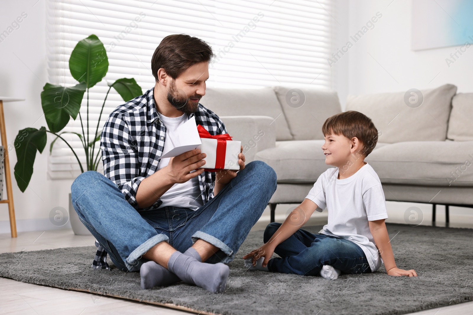 Photo of Happy dad with gift and greeting card for Father's Day from his son at home