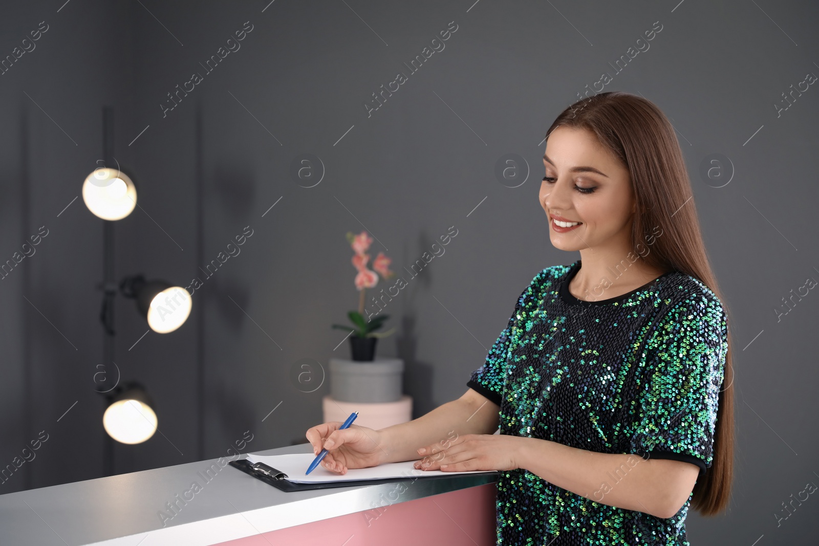 Photo of Young woman filling application form at reception desk in beauty salon