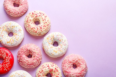 Photo of Delicious glazed doughnuts on color background, top view