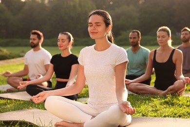 Photo of Group of people practicing yoga outdoors on sunny day, selective focus. Lotus pose