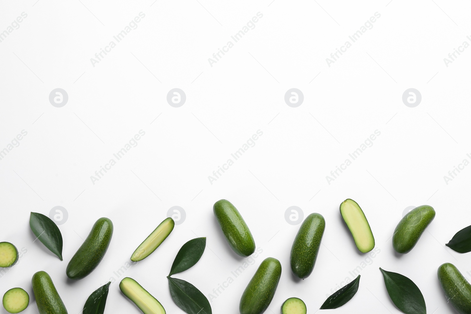 Photo of Whole and cut seedless avocados with green leaves on light background, flat lay. Space for text