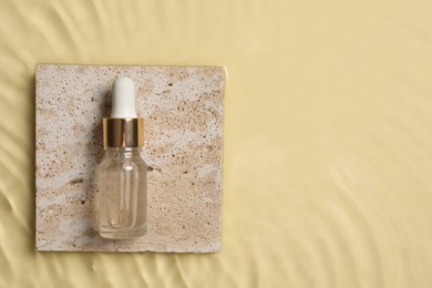 Bottle of cosmetic serum and water on beige background, top view. Space for text