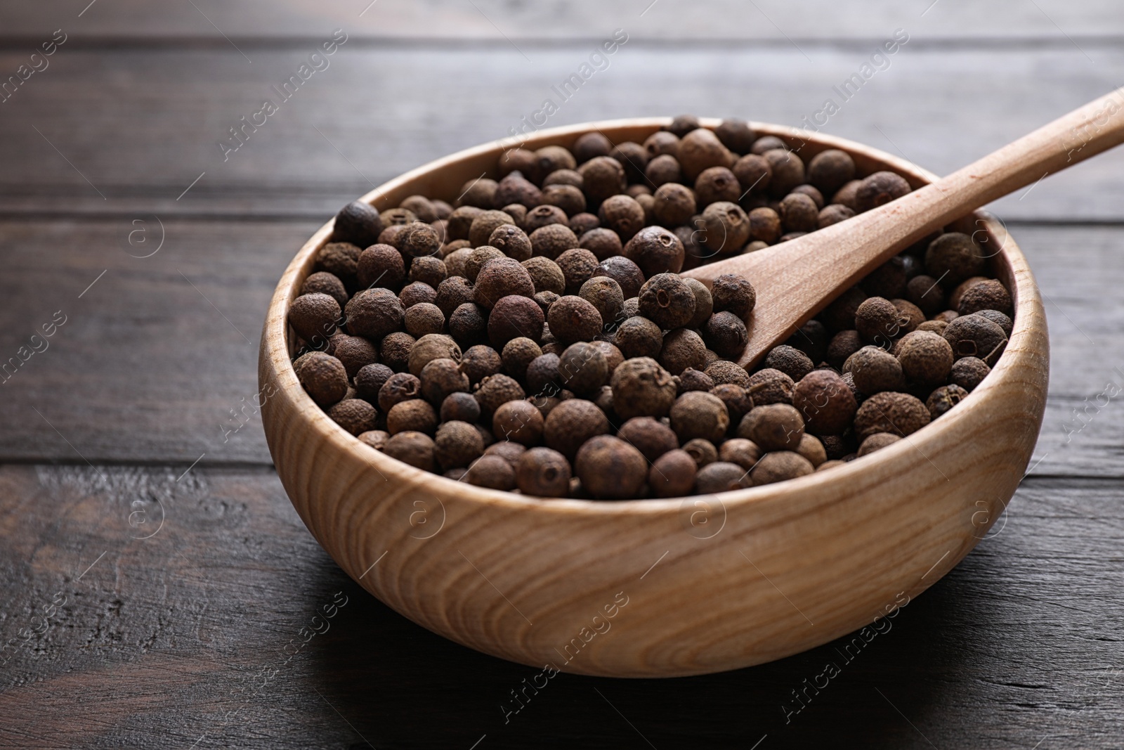 Photo of Peppercorns in bowl on wooden table, closeup