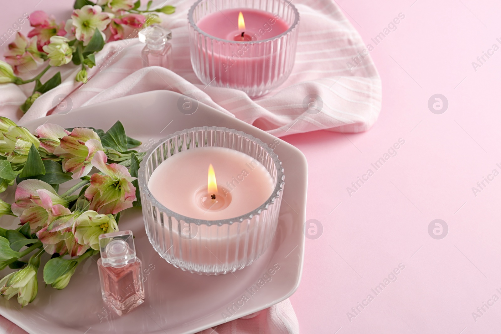 Photo of Stylish tender composition with burning candles and flowers on pink background. Cozy interior element