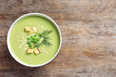 Photo of Fresh vegetable detox soup made of green peas in dish on wooden background, top view with space for text