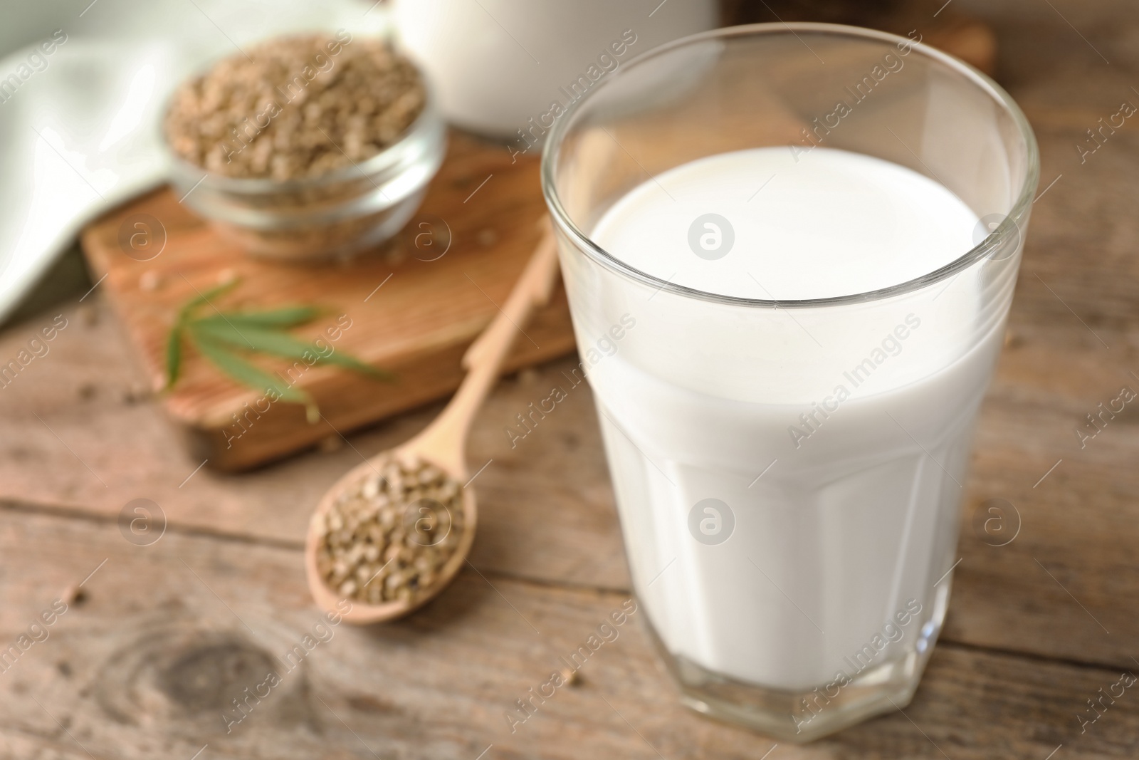 Photo of Composition with glass of hemp milk on wooden table, closeup. Space for text