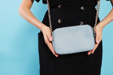 Photo of Woman with stylish bag on light blue background, closeup