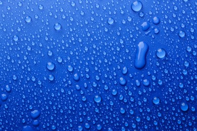 Photo of Water drops on blue background, top view