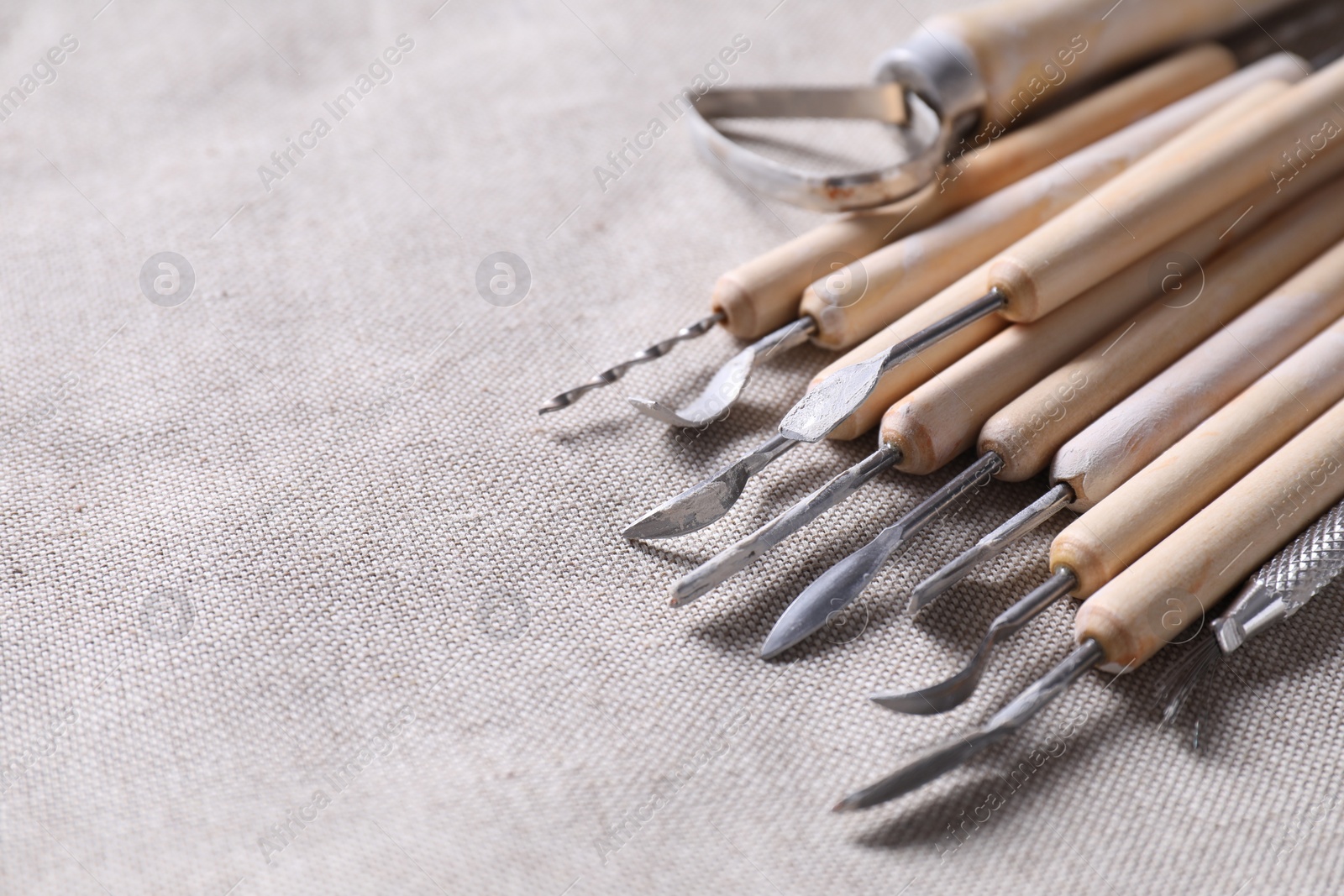 Photo of Set of different clay crafting tools on grey fabric, closeup. Space for text