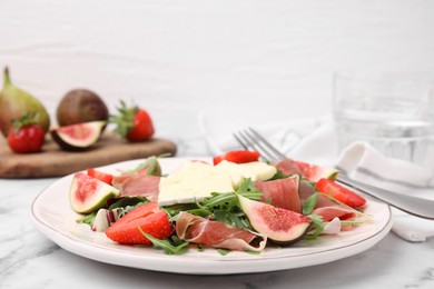 Photo of Tasty salad with brie cheese, prosciutto, strawberries and figs on white marble table