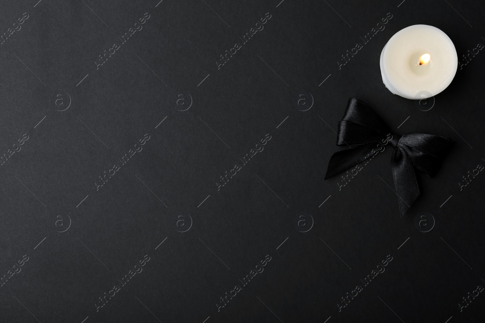 Photo of Ribbon and candle on black background, top view. Funeral symbols