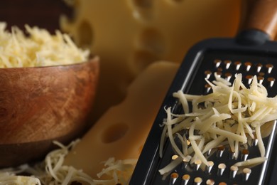 Photo of Grated, cut cheese and grater on table, closeup