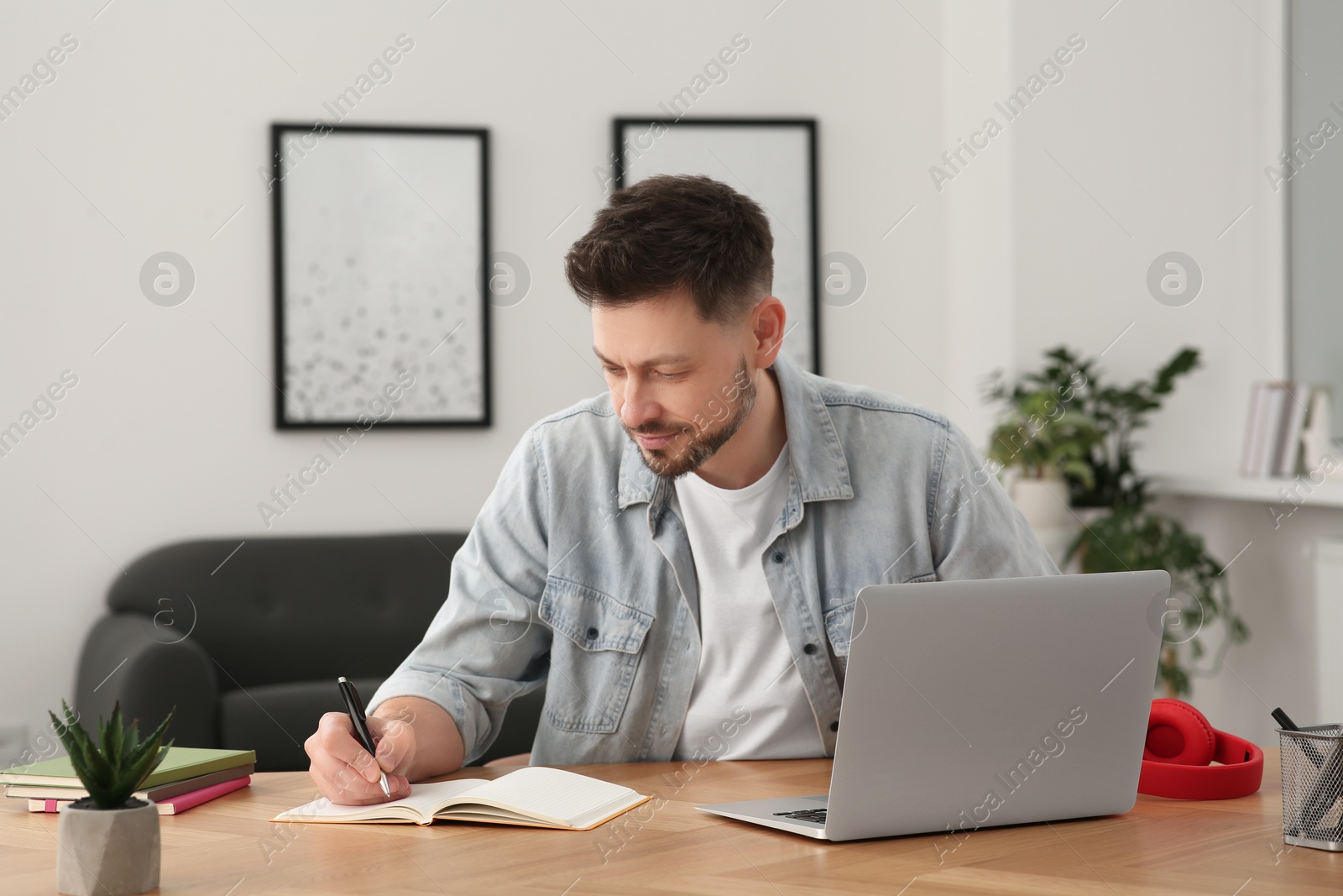 Photo of Online translation course. Man writing near laptop at home