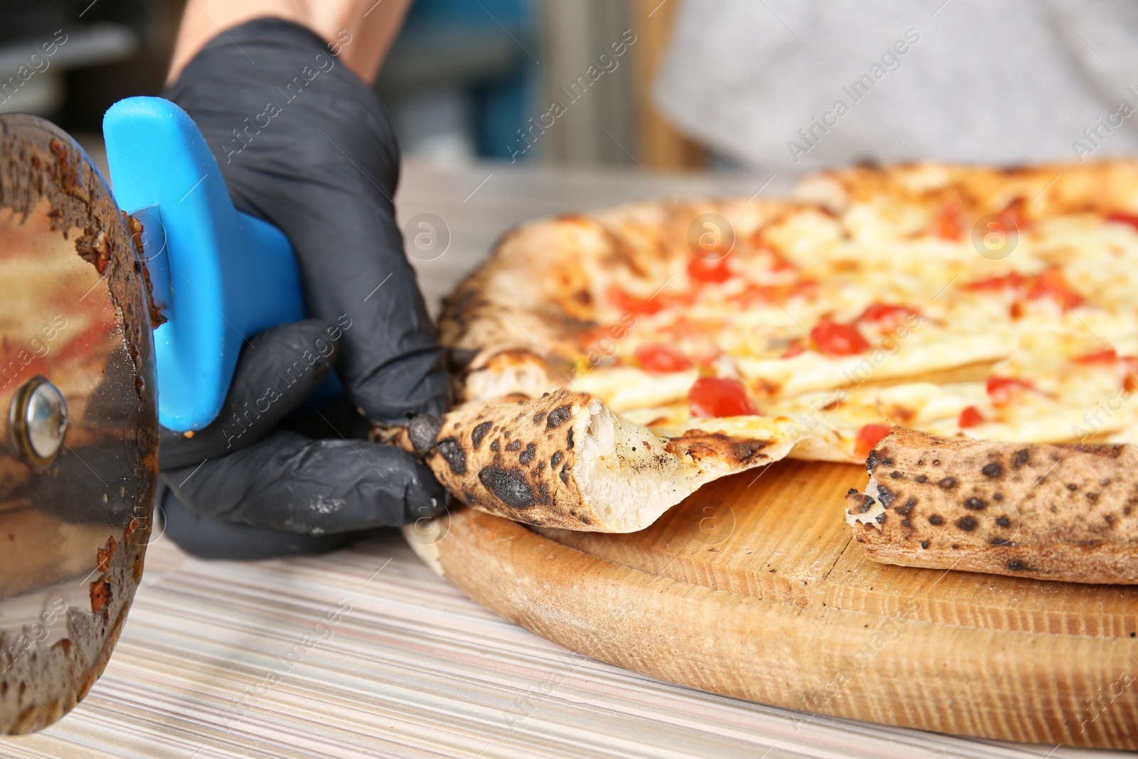 Photo of Professional chef cutting Italian oven baked pizza in restaurant, closeup