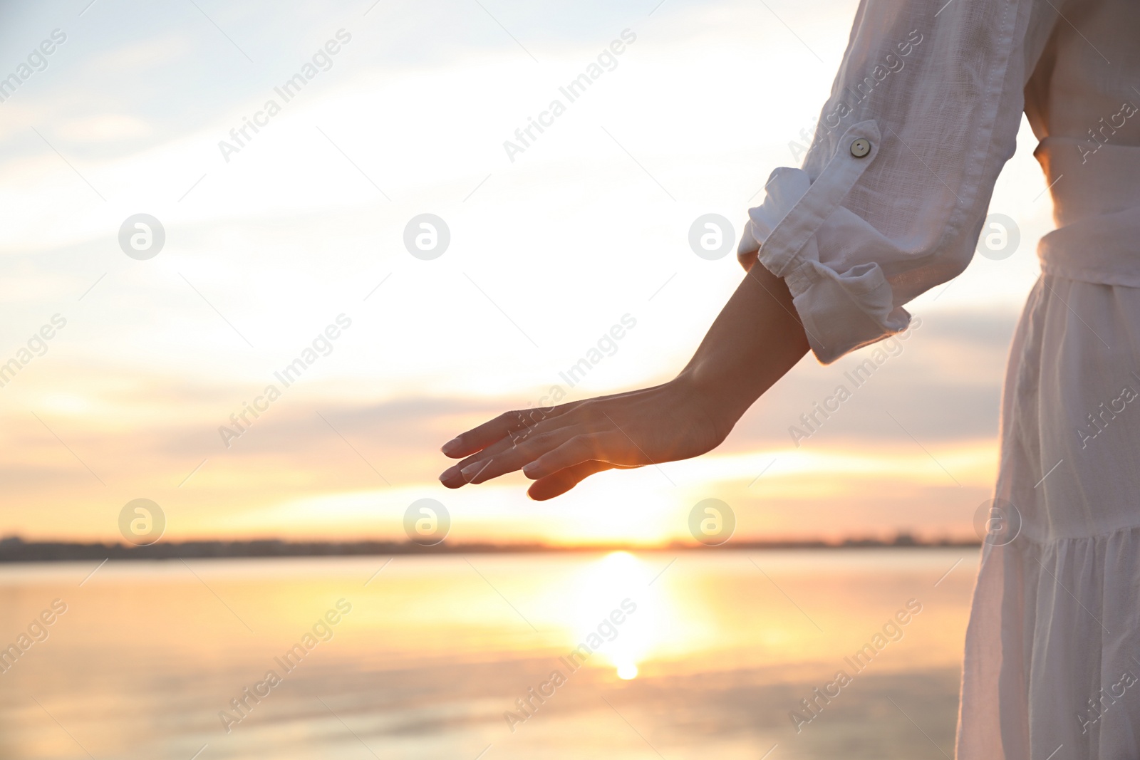 Photo of Young woman near river at sunset, closeup. Nature healing power