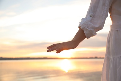 Young woman near river at sunset, closeup. Nature healing power