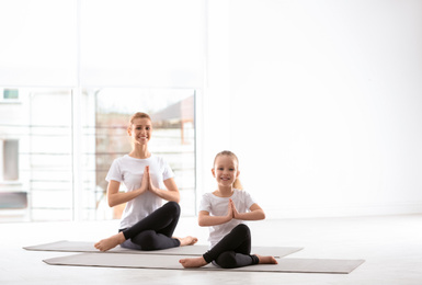 Mother and daughter in matching sportswear doing yoga together at home