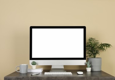 Modern computer, decor and office supplies on wooden table near beige wall