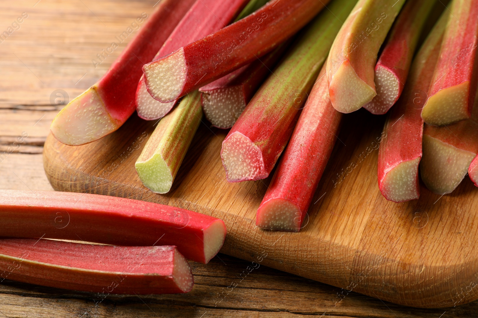 Photo of Many cut rhubarb stalks on wooden table, closeup