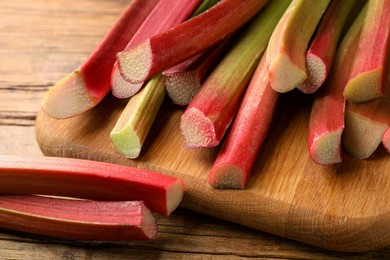 Many cut rhubarb stalks on wooden table, closeup