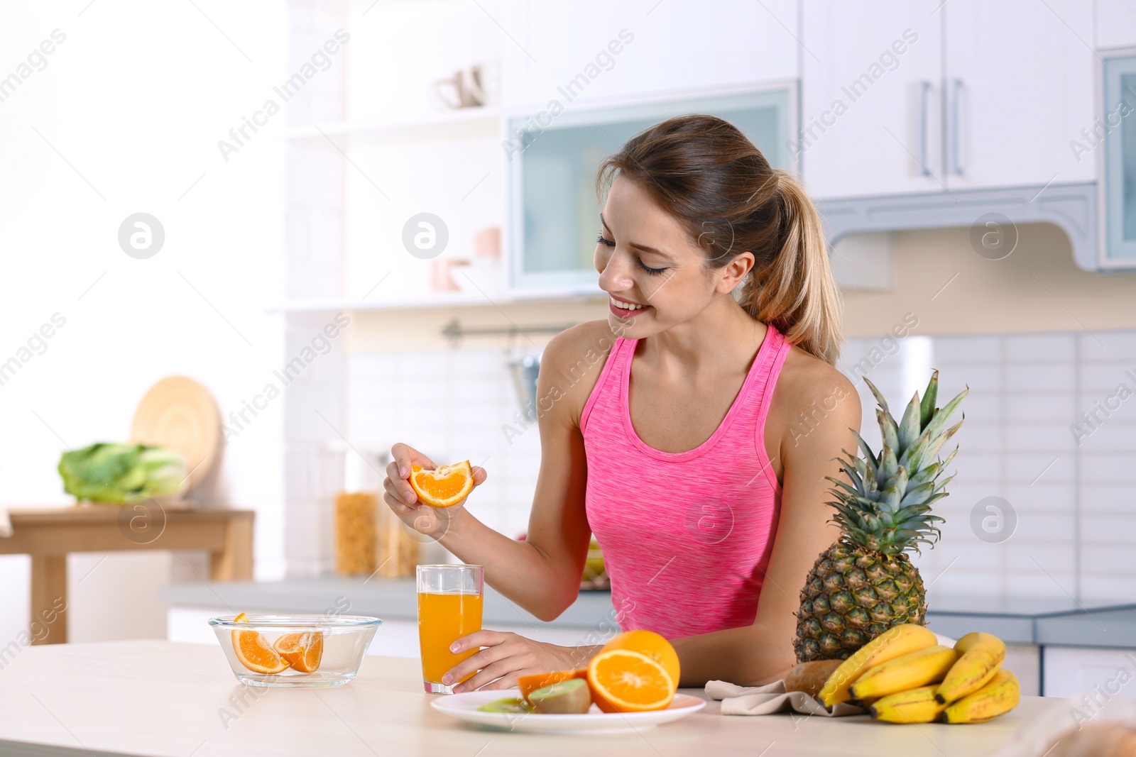 Photo of Woman making orange juice at table in kitchen. Healthy diet