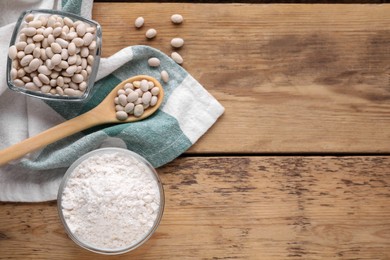 Photo of Kidney bean flour and seeds on wooden table, flat lay. Space for text