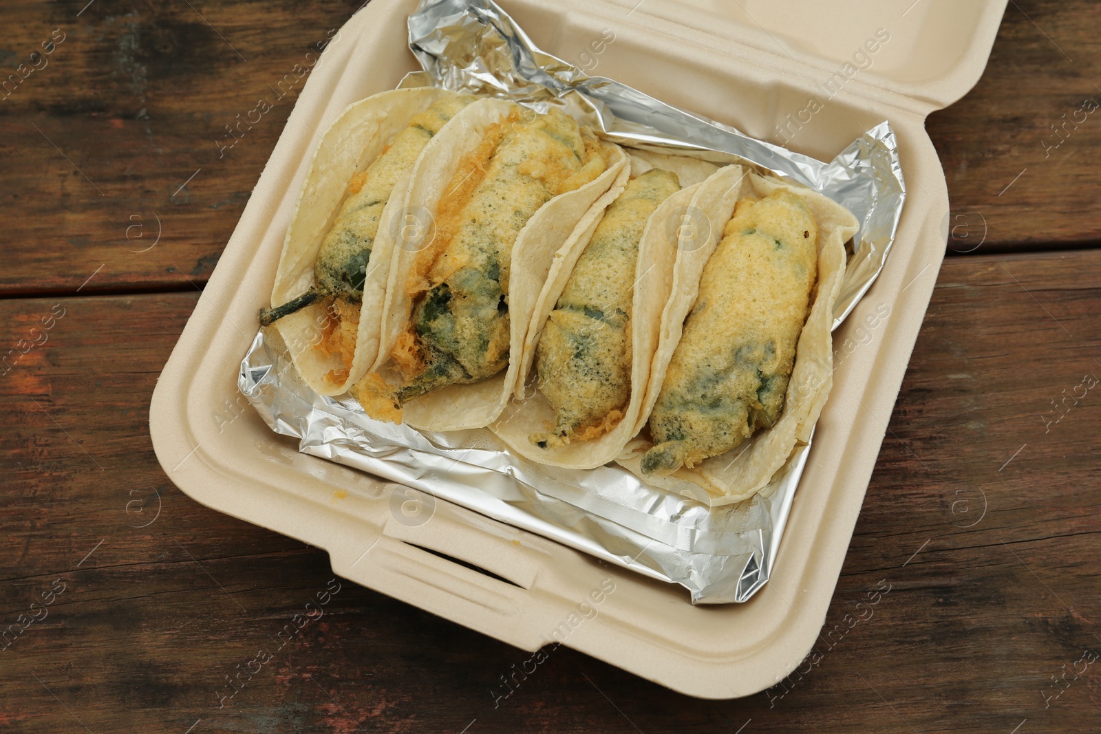 Photo of Jalapeno peppers stuffed with cheese in box on wooden table, above view